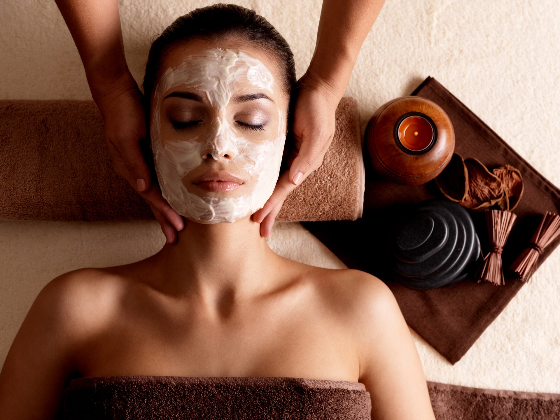 Woman with facial mask getting massage at spa